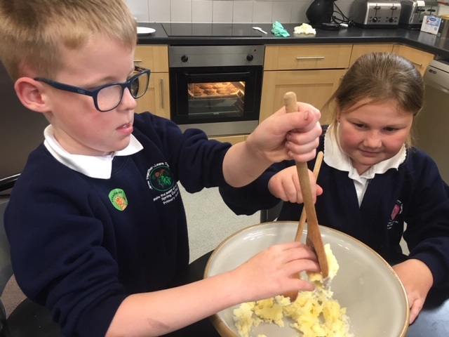 two children baking, stirring a bowl with a wooden spoon